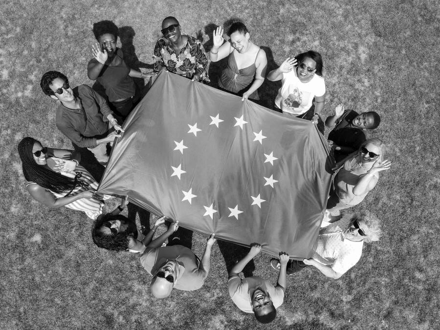 A multicultural group holding a European flag